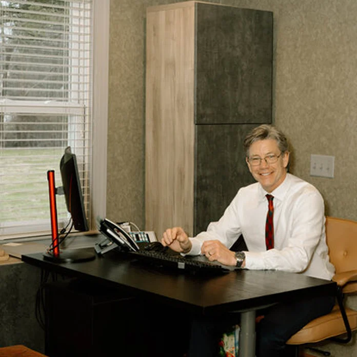 Dentist at desk in office with computer and professional attire