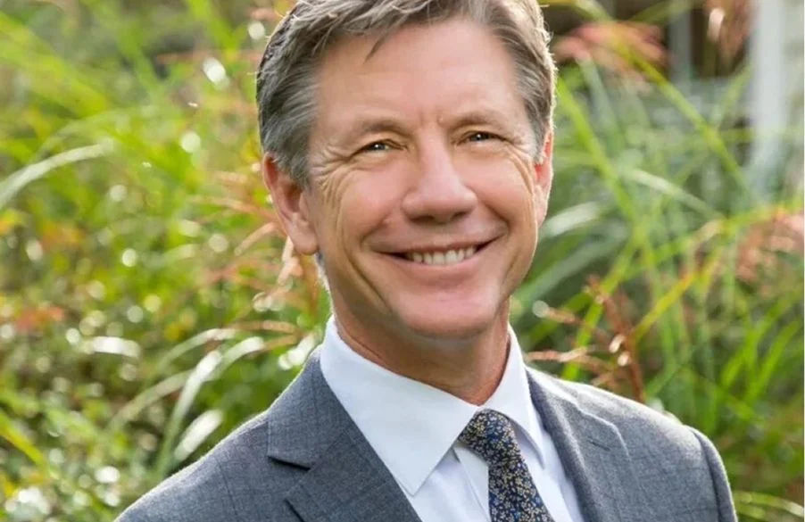Professional portrait of male dentist in gray suit and patterned tie outdoors