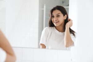 Woman smiling confidently at her reflection in a mirror